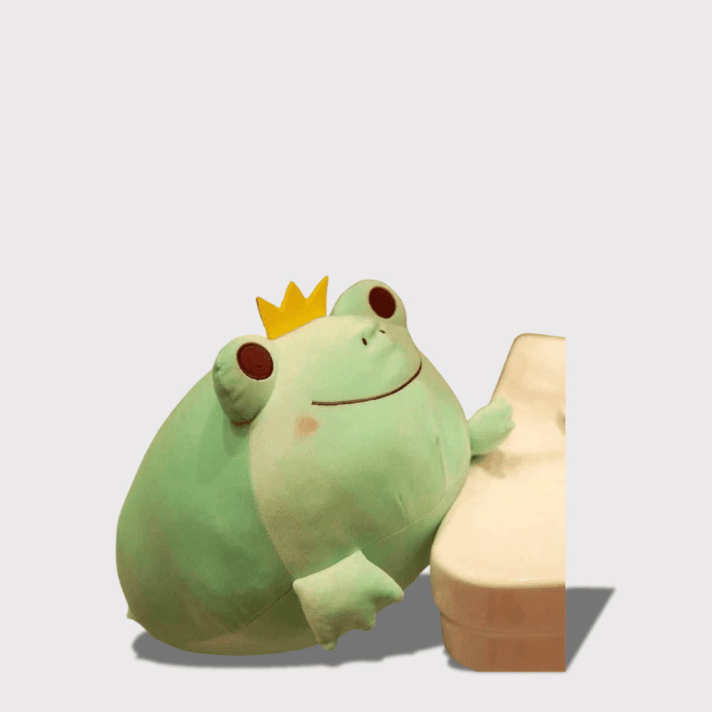 Doudou Grenouille Prince en Vert 35 cm : Doudou grenouille verte avec une couronne, appuyée sur un meuble blanc.