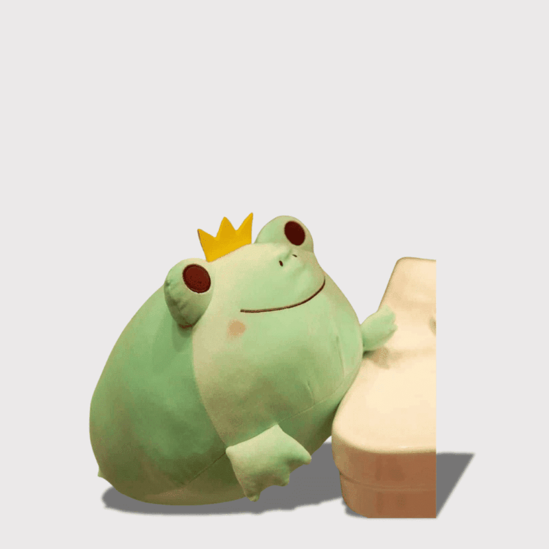 Doudou Grenouille Prince en Vert 35 cm : Doudou grenouille verte avec une couronne, appuyée sur un meuble blanc.