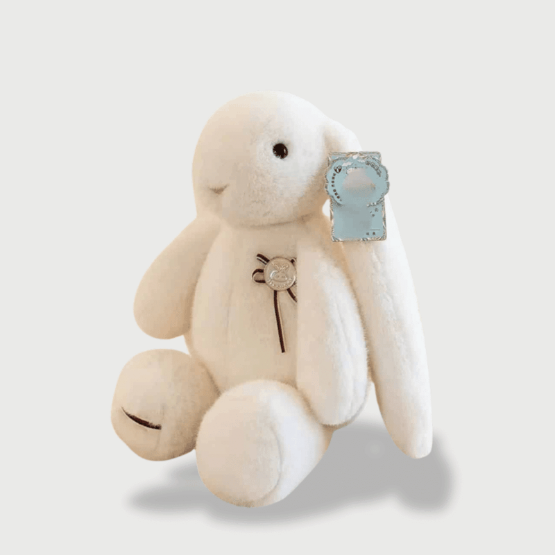 Doudou Lapin Longues Oreilles : Doudou lapin blanc avec longues oreilles tombantes et badge décoratif.