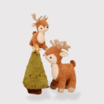 Doudou Biche de Noël Stylé : Sapin de Noël avec une étoile, accompagné d'un doudou biche marron avec des cornes en bois posées dessus, et d'un autre doudou biche marron avec des cornes en bois à côté.