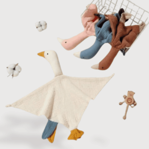 Doudou Canard Plat en Coton : Doudou canard en tissu beige avec ailes étendues, pattes bleues et bec jaune, accompagné de plusieurs doudous similaires de couleurs marron, bleu et rose dans un panier.