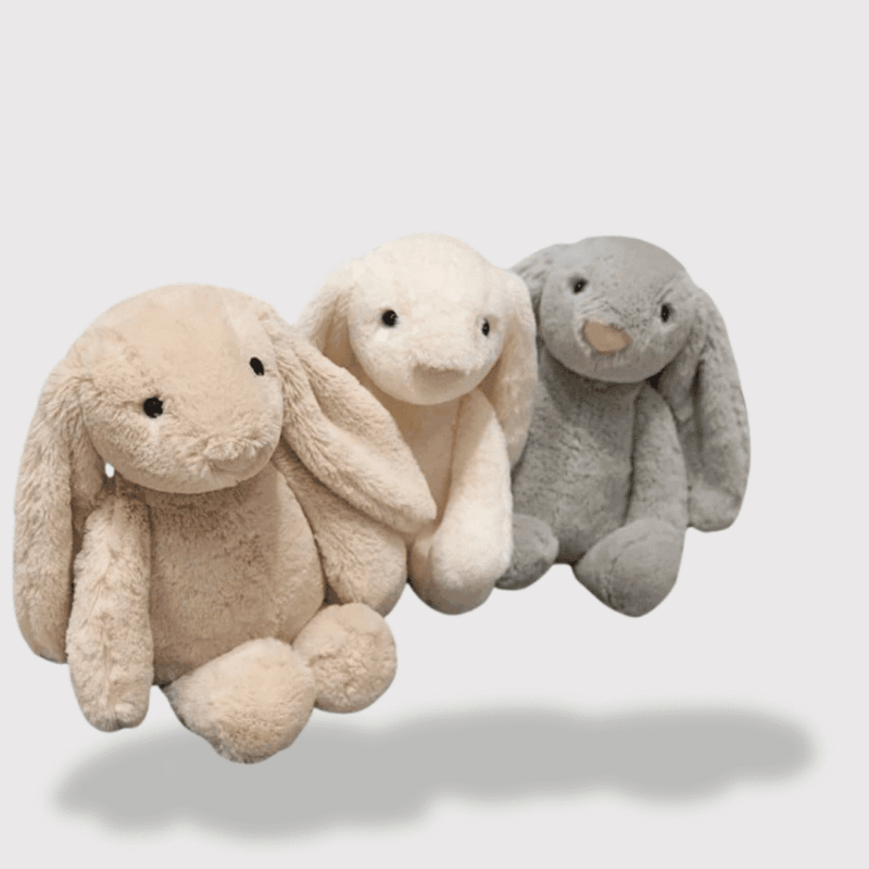 Doudou Bébé Lapin Doux 20 cm composé de trois lapins moelleux beige, blanc et gris, aux grandes oreilles tombantes et souriantes.