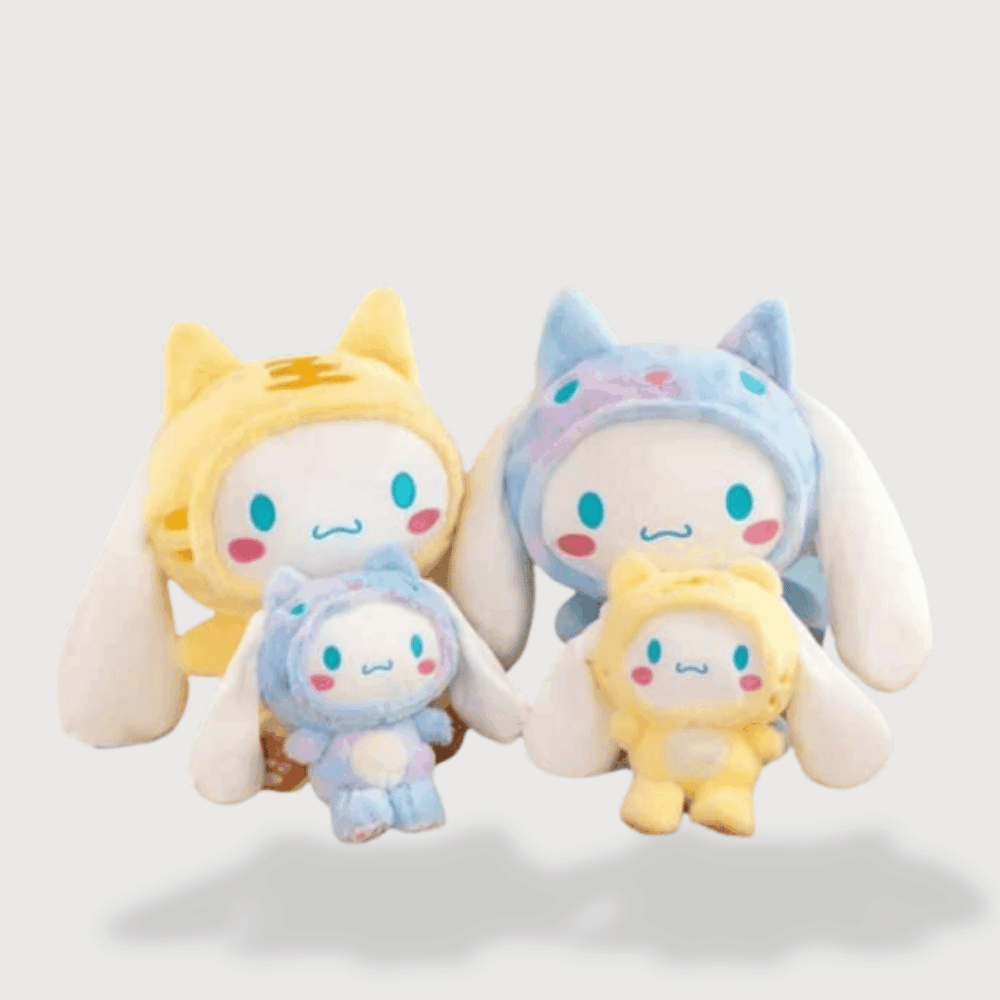 Doudou Peluche Cinnamoroll Déguisé en Chat montrant Cinnamoroll blanc portant un bonnet de chat jaune et bleu, avec des joues roses.
