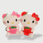 Doudou Kawaii Hello Kitty : Deux doudous Hello Kitty blancs, l’un en robe rose avec une fraise et un nœud rose, l’autre en robe rouge avec une fraise et un nœud rouge.