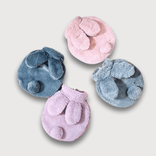 Doudou Bouillotte Lapin Doux : Quatre bouillottes en forme de lapin aux couleurs pastel (bleu, gris, rose, violet) avec des oreilles rabattues.