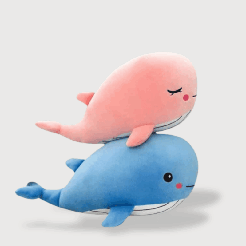 Doudou Baleine Ultra-Doux : Deux doudous, l'un représentant une baleine rose avec les yeux fermés et l'autre une baleine bleue avec les yeux ouverts, toutes deux affichant un sourire.
