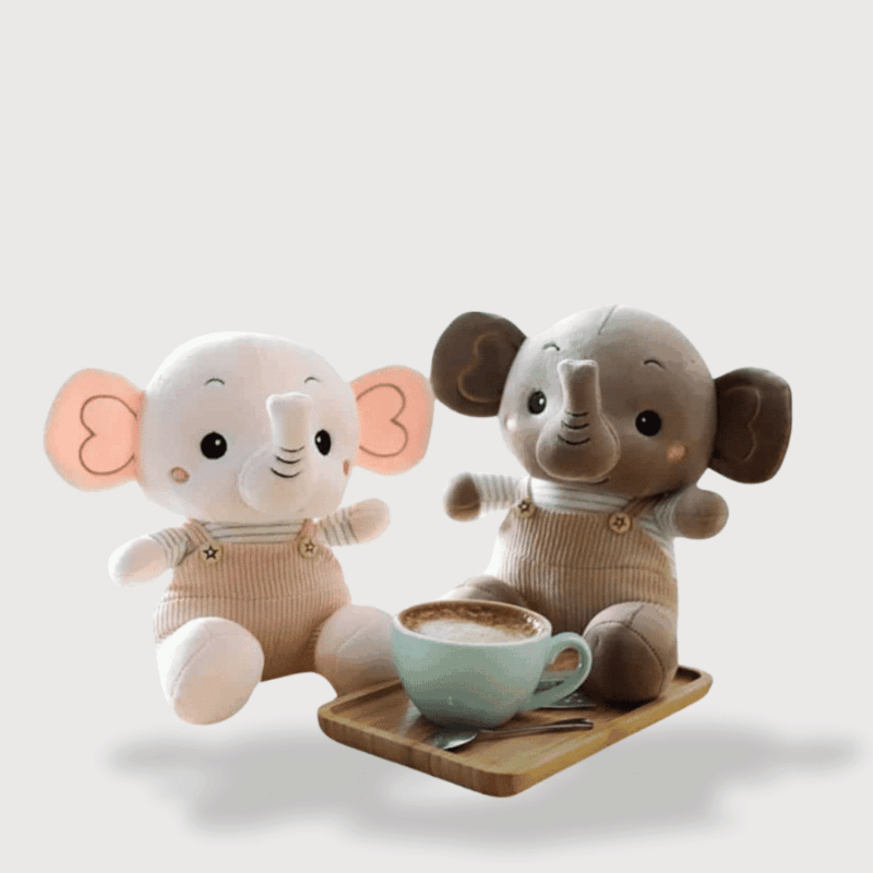 Doudou Eléphant Très Douce, deux éléphants kawaii assis en salopette beige et grise devant une tasse.