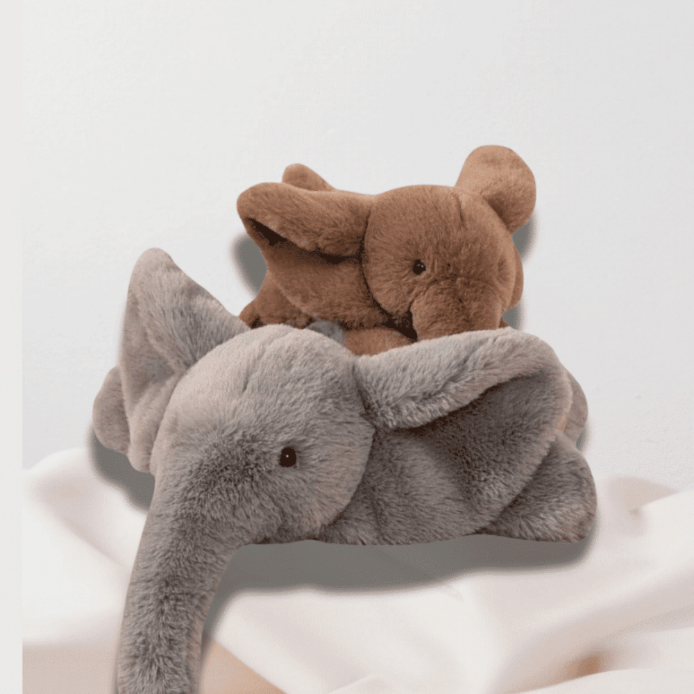Doudou Élément avec Grandes Oreilles, deux doudous éléphants allongés sur un drap, l'un marron et l'autre gris.